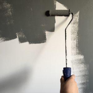 Painting gray paint on a white wall