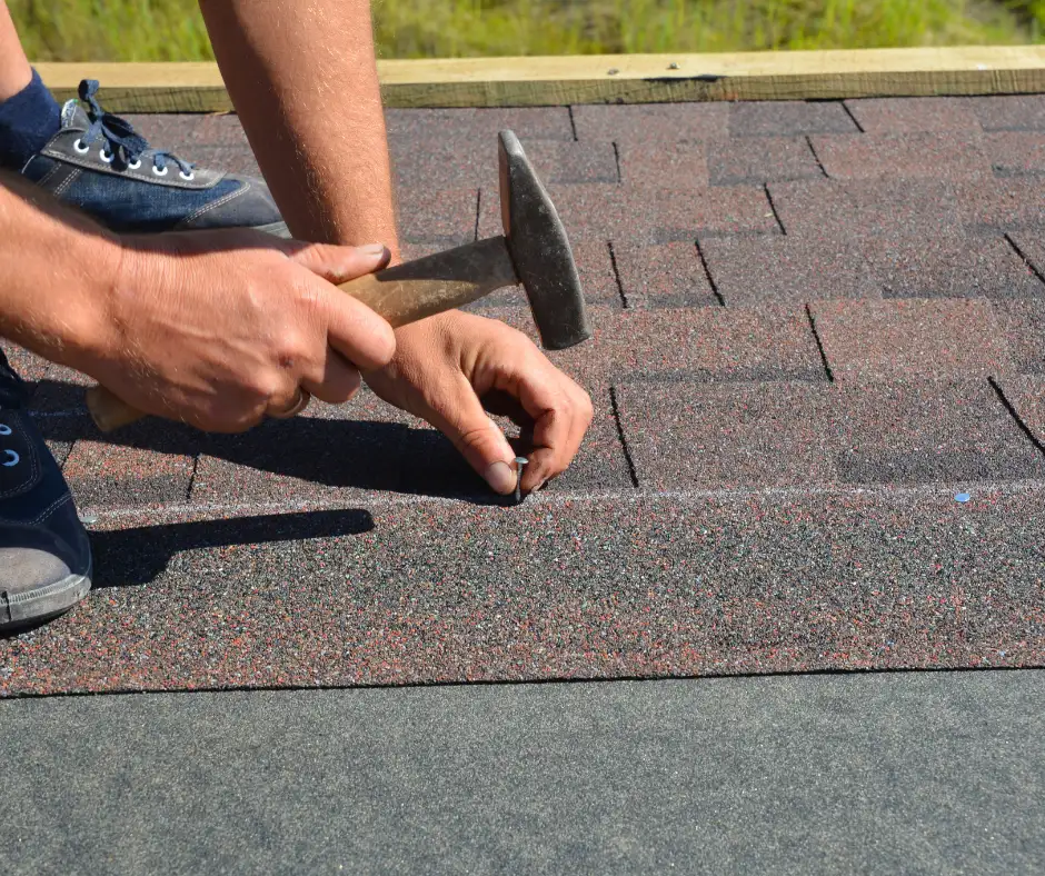 a hand hammering a nail on the roof