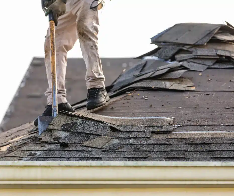 a man holding a shovel removing old roofs