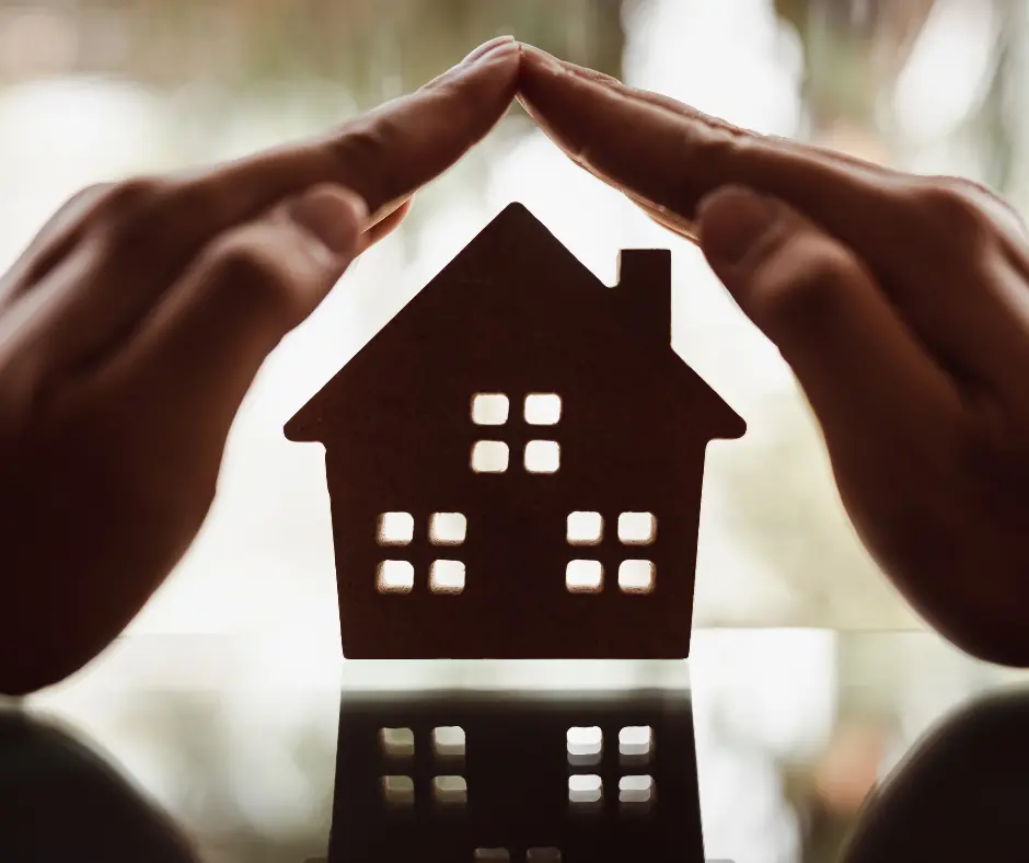 hands covering a miniature house representing affordable roofing services
