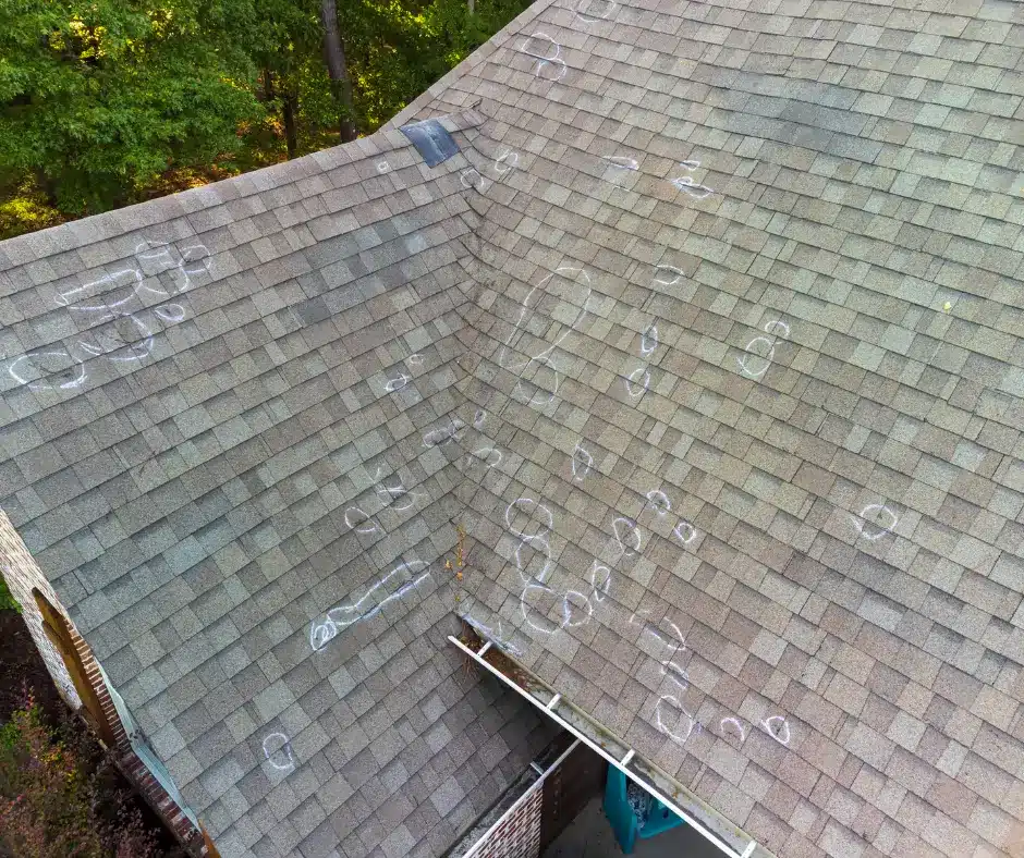 An aerial view of a shingle roof with numerous hail damage marks circled in white chalk. Examples of top roofing shingles for hail