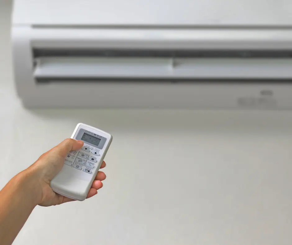 A hand holding an AC remote.