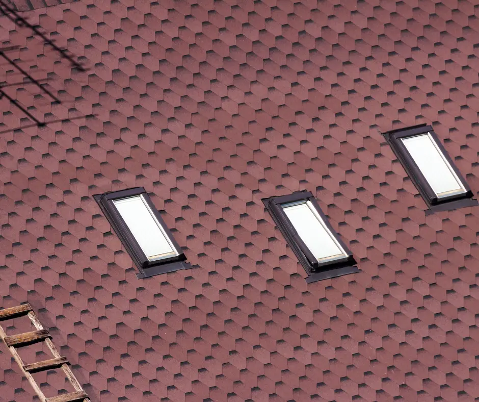 Dark red hexagonal roofing shingles with three skylights. Best roofing shingles for cold climates