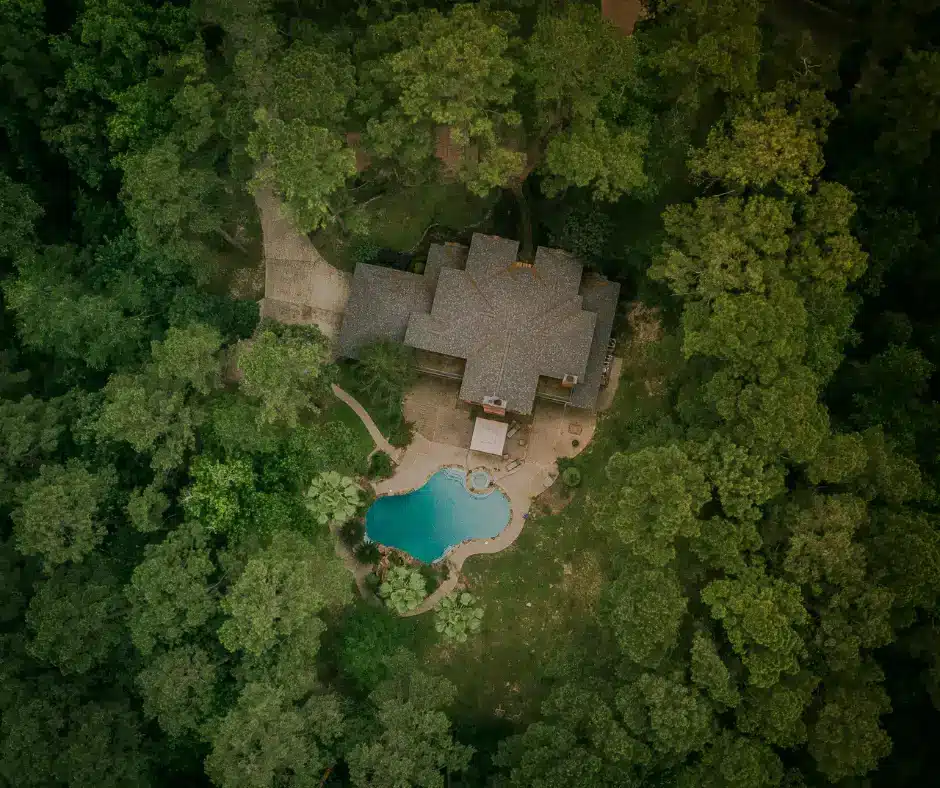 Aerial view of large residential roof built with roofing financing contractor surrounded by pool and mature trees