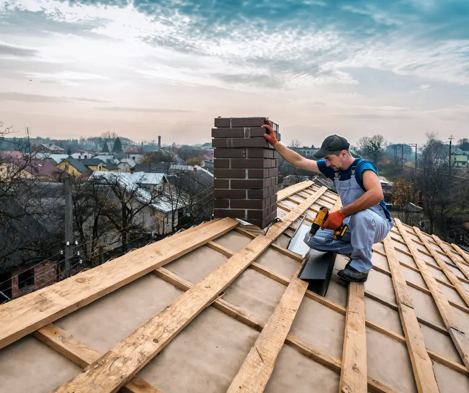 Roofer in safety gear working on wooden roof frame construction with nail gun