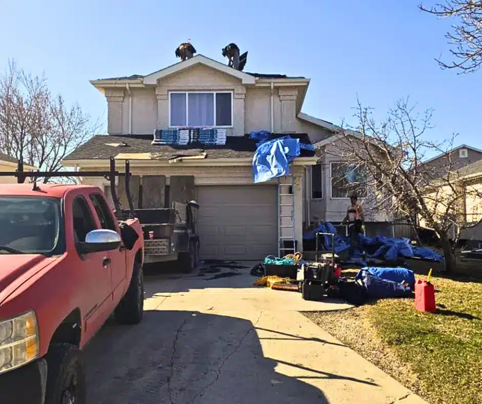 All Weather Exteriors Roofing crew working on shingle replacement on suburban two-story home.