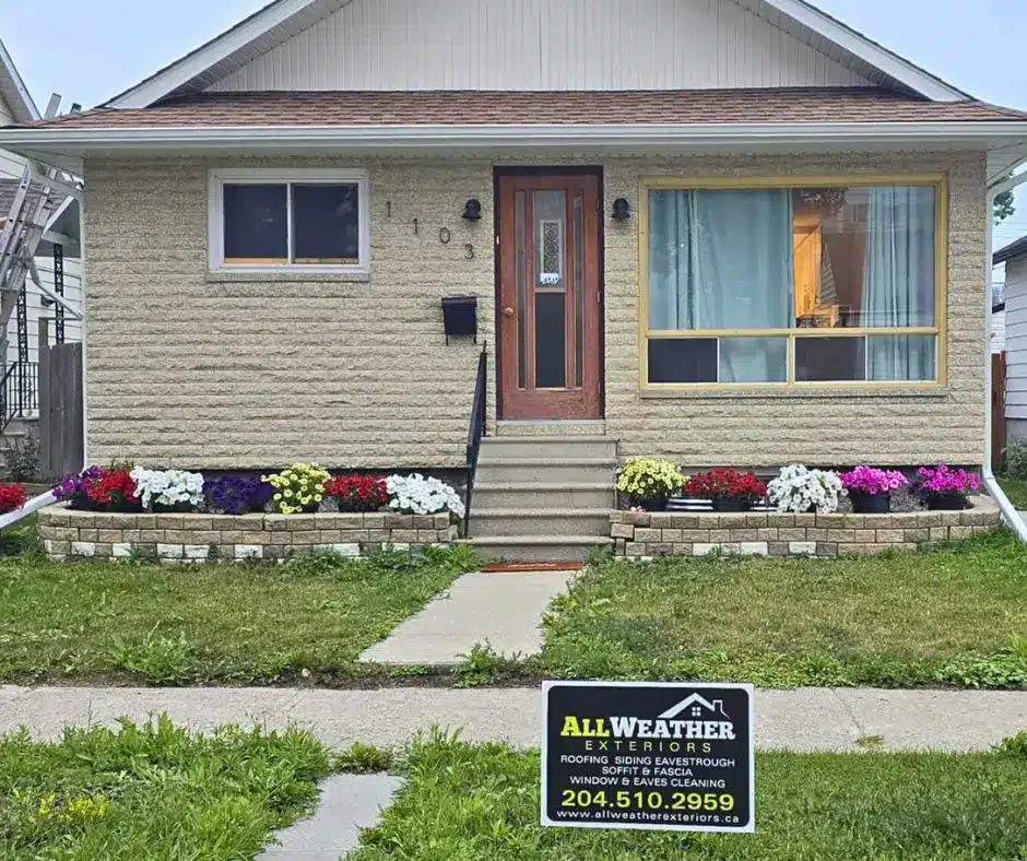 Front view of Winnipeg home with flower beds and All Weather Exteriors sign.
