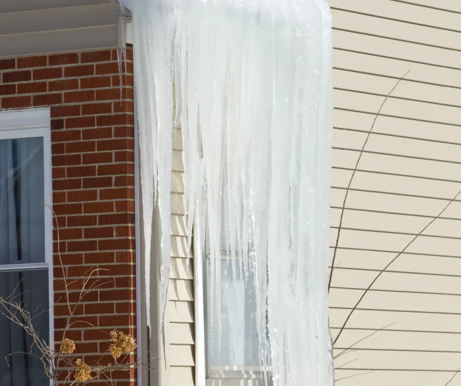 Icicles hanging from the edge of a house roof. A sign to remove ice dams on your roof