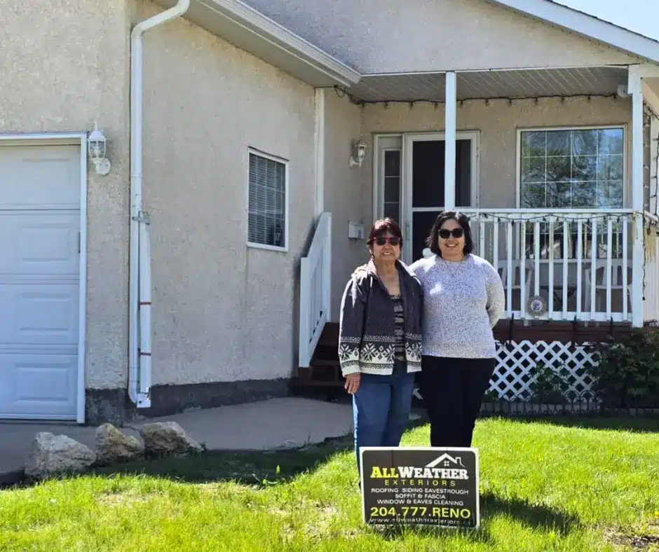 Two homeowners standing by front porch with All Weather Exteriors yard sign on lawn. They are happy for the professional Winnipeg roofing services by All Weather Exteriors