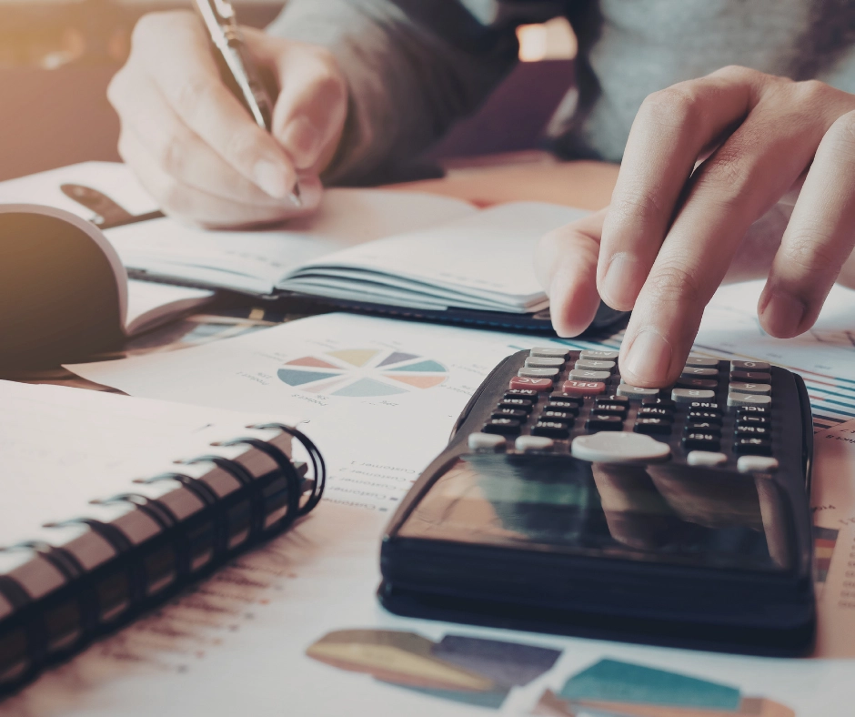 A homeowner using a calculator and notepad to budget for potential additional roof replacement costs and material expenses.