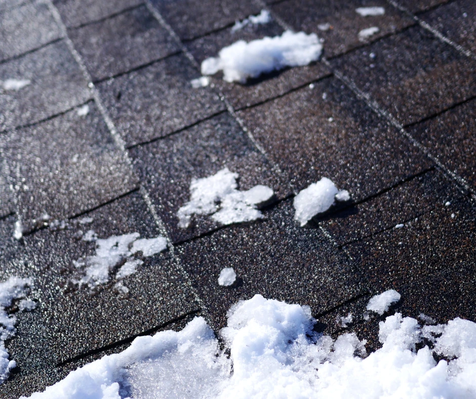 Close-up of snow and ice on asphalt shingles, illustrating why a standard off-season roof replacement is technically challenging in extreme cold.