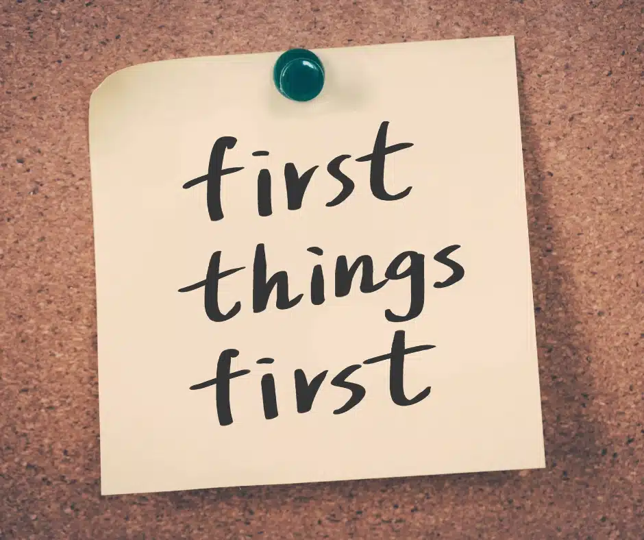 A sticky note reading "first things first" on a corkboard, highlighting the essential project rule.
